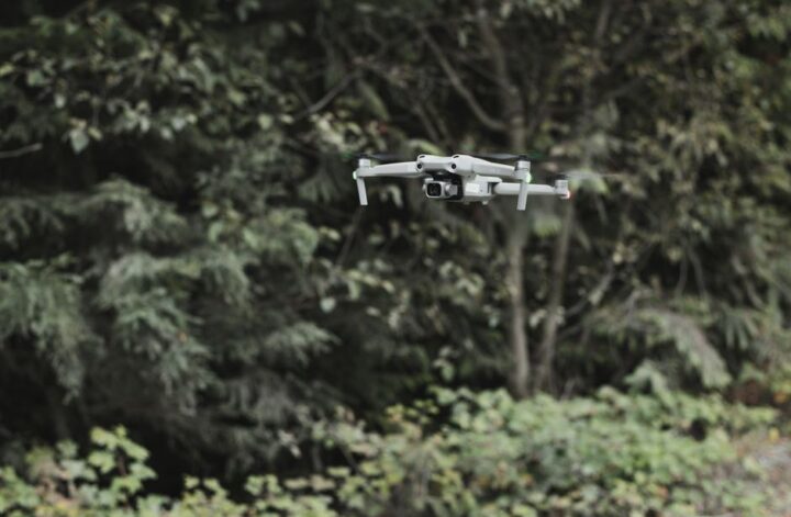 Aerial view of a dense forest with a UAV capturing data for forestry mapping.
