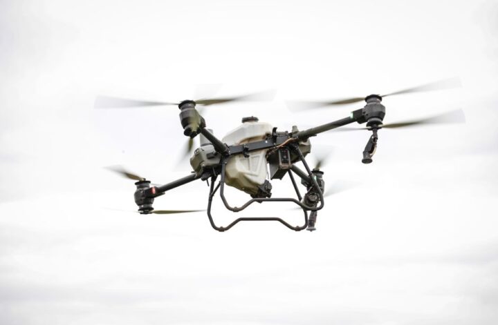A drone flying over a landscape surveying land with high-resolution cameras and sensors.